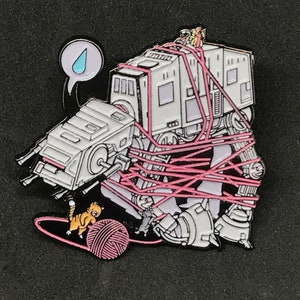 May include: A white AT-AT walker is tangled in pink yarn. A small orange cat is holding a ball of yarn. A speech bubble above the walker contains a blue teardrop.