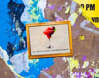 Puede incluir: Una ilustración enmarcada de una margarita de fresa congelada roja con una guarnición de fresa. El texto debajo de la imagen dice "Ceci n'est pas une frozen strawberry margarita."
