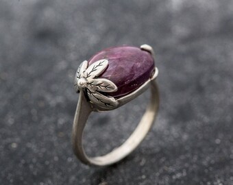 May include: A silver ring with a purple gemstone set in a floral design.
