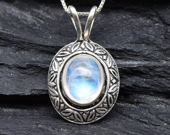 May include: A silver pendant necklace with a moonstone oval cabochon set in a detailed silver frame. The pendant is on a silver chain.