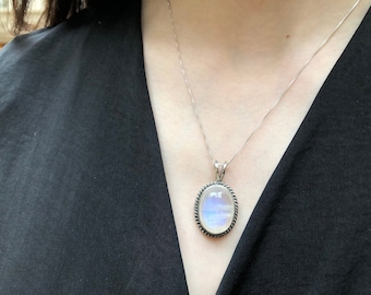 May include: A silver chain necklace with a silver oval pendant featuring a large iridescent moonstone.