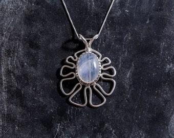 May include: A silver pendant necklace with a white moonstone set in a delicate, floral-shaped design.
