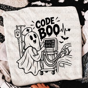 Puede incluir: Una camiseta de color claro con un gráfico negro de un fantasma con cofia de enfermero, junto a un monitor médico y una bolsa de suero ICU. El texto dice CODE BOO, acompañado de una línea de ritmo cardíaco y dos pequeños murciélagos.