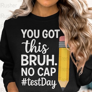 Puede incluir: Sudadera negra con texto blanco que dice "You got this bruh. No cap #testDay" y un lápiz amarillo con una goma rosa.