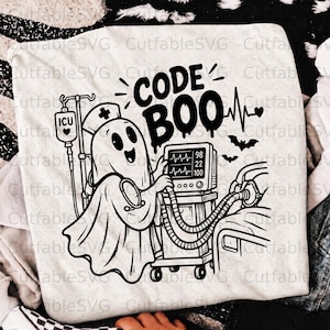 Puede incluir: Una camiseta de color claro con un gráfico negro de un fantasma con cofia de enfermero, junto a un monitor médico y una bolsa de suero ICU. El texto dice CODE BOO, acompañado de una línea de ritmo cardíaco y dos pequeños murciélagos.