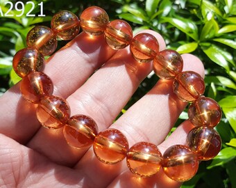 May include: A bracelet made of round, translucent, amber-colored beads. The beads have a golden shimmer and are strung together on a clear elastic cord.