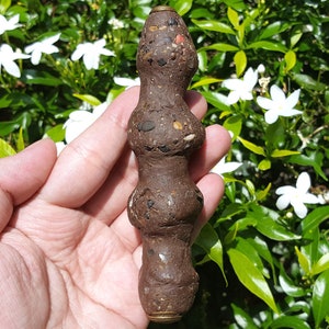 Könnte beinhalten: Eine braune und schwarze Perlenkette mit goldenen Akzenten. Die Perlen bestehen aus einem rauen, strukturierten Material und sind zu einer langen, zylindrischen Form zusammengefügt.