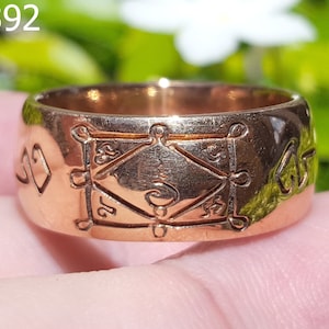 Op de afbeelding: Een koperen ring met een decoratief ontwerp met een vierkant met een cirkel erin en andere symbolen. De ring is gegraveerd met de tekst "AA3392".