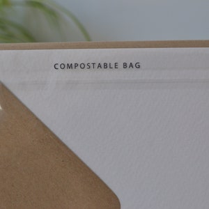 May include: Close-up of a white paper bag with the text "COMPOSTABLE BAG" printed on it.
