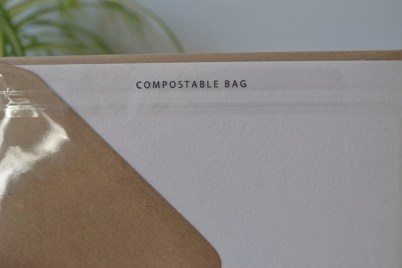 May include: Close-up of a white paper bag with the text "COMPOSTABLE BAG" printed on it.