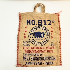 May include: A burlap bag with a handle, featuring the text "NO.817" and "Elephant Brand" with an elephant logo. The bag also states "Net Wt. 4.55 KG. 10 LBS." and "Indian Basmati Rice". The bag has red stitching.