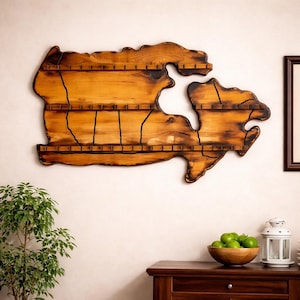 May include: A wooden wall-mounted display in the shape of Canada. It features multiple shelves and is made of light brown wood with darker edges. Black lines mark the provinces and territories.