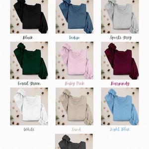 May include: A product image showcasing a variety of crewneck sweatshirts in different colors. The available colors include black, indigo, sports grey, forest green, baby pink, burgundy, white, sand, light blue, and heather grey. The text "Colour Options" is at the top.