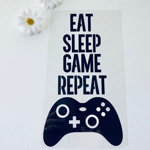 May include: Black and white vinyl sticker with a video game controller and the text "Eat Sleep Game Repeat".