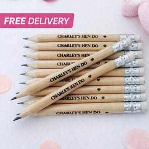 May include: A stack of wooden pencils, each with an eraser and the inscription "CHARLEY'S HEN DO" along with heart symbols. The pencils are made of natural wood and are arranged in a neat pile.