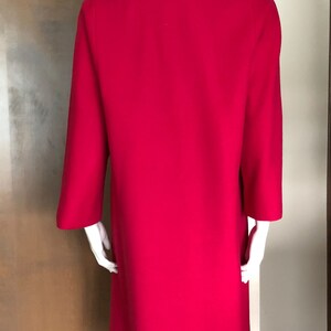 Puede incluir: Un abrigo rosa brillante con un cuello de piel marr&oacute;n. El abrigo tiene mangas largas y un dise&ntilde;o simple y cl&aacute;sico.