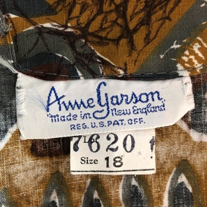 May include: Close-up of a vintage fabric with a repeating pattern in shades of brown, green, and white. The label reads "Anne Garson, Made in New England, Size 18".