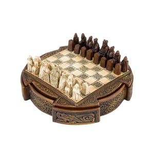 Op de afbeelding: Een decoratief schaakspel met ingewikkeld gesneden stukken in ivoor- en bruintinten. Het schaakbord is vierkant met een patroon, geplaatst in een ronde, houten basis met gedetailleerde gravures. De stukken zijn gestileerde figuren.