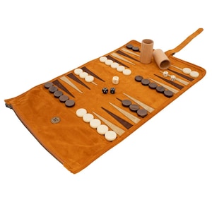 May include: A rolled-up backgammon set with a tan playing surface and brown and white game pieces. The set includes dice, dice cups, and a zippered carrying case. The game board is open and ready for play.