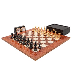 May include: A complete chess set with a wooden board featuring a brown and cream checkered pattern. The set includes black and cream chess pieces, a chess clock, and a wooden storage box. The board has a reddish-brown border.