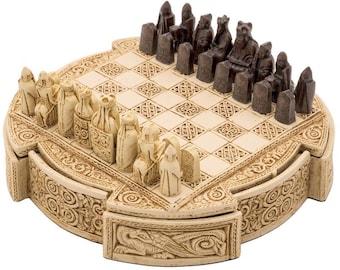 Könnte beinhalten: Ein detailliertes Schachspiel mit einem cremefarbenen Brett und aufwendig geschnitzten Figuren. Die Schachfiguren sind in zwei Farben gehalten, Creme und Dunkelbraun. Das Brett ist mit keltischen Knotenmustern verziert. Das Set befindet sich in einer dekorativen, runden Box.