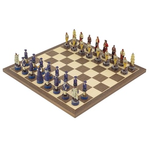 May include: A complete chess set with intricately detailed pieces. The chess pieces are painted in shades of blue, red, and cream, and are arranged on a wooden chessboard with a checkered pattern. The set is displayed on a light background.