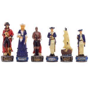 May include: A set of six chess pieces with a pirate theme. The pieces include a king, queen, bishop, knight, castle, and pawn. Each piece is painted with vibrant colors and detailed designs, with the names of the pieces on the base.