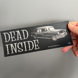 May include: A black rectangular sticker with the words "DEAD INSIDE" in white, stylized text. A detailed illustration of a vintage hearse is on the right. The website "WIREHEDLABORATORIES.COM" is printed at the bottom.