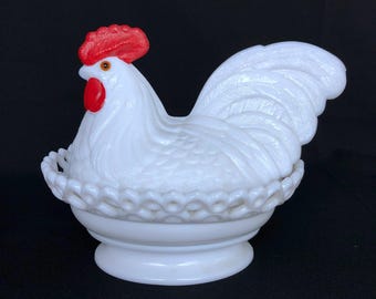 May include: White milk glass rooster with a red comb and wattles sitting in a white milk glass nest.