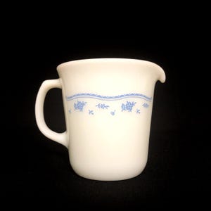 May include: A white ceramic mug with a black handle and the text "But First, Coffee" in a black, bold font. The mug is on a white surface.
