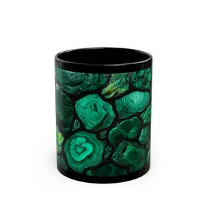 May include: Black ceramic mug featuring a vibrant malachite stone pattern. The design showcases a mosaic of deep green and lighter green swirls and shapes, creating a natural, earthy aesthetic. The mug has a glossy finish and a solid black rim and interior.