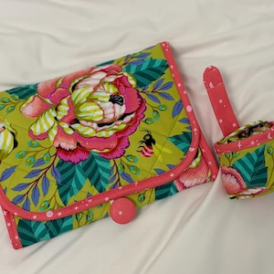 May include: A quilted fabric organiser case and a matching small cylindrical pouch. Both items feature a vibrant floral pattern with large pink peonies, green leaves, and small bees on a lime green background, finished with pink star-patterned trim.