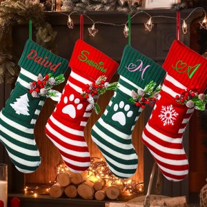 Puede incluir: Cuatro calcetines de Navidad personalizados con patrones de rayas rojas y verdes. Los calcetines tienen un diseño de huella de pata, copo de nieve y árbol de Navidad. Los nombres "David", "Sabrina", "M" y "A" están bordados en los calcetines.