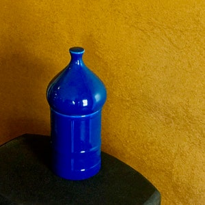 May include: A blue ceramic jar with a rounded lid. The jar is sitting on a black surface.