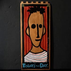 May include: A rectangular, hand-painted artwork featuring a stylized face with black hair and large eyes. The background has vertical red stripes. The text "TODAY'S THE DAY" is at the bottom. Signed "NYC 5.13 matthew courtney".