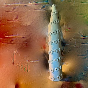 May include: A tall, off-white ceramic sculpture with a conical shape. The sculpture is adorned with evenly spaced, circular, raised details. The background features a blend of colors, including orange, green, and brown.