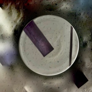 May include: A white ceramic plate with a crackled glaze and two black and purple stripes. The plate has a textured surface.