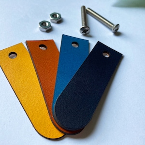 May include: Four leather swatches in yellow, orange, blue, and black. The swatches are arranged in a fan shape with the yellow swatch at the top.