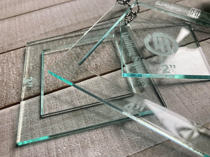 May include: A set of three clear acrylic quilting rulers with etched measurements in inches. The rulers are labeled "Quilting Squares" and "LaserHawk".