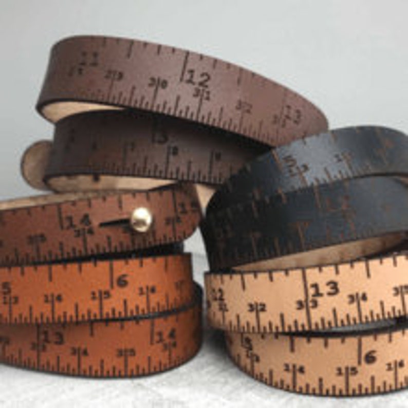 May include: A set of four leather bracelets with a ruler design. The bracelets are in brown, black, tan, and light brown. Each bracelet has a different measurement scale.