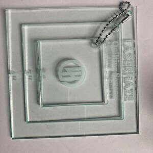 May include: Three clear glass squares with a chain attached to the largest square. The squares are labeled "Lagenfaze Quilting Squares".