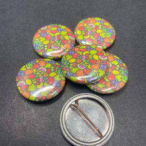 May include: Five colorful fruit-patterned button pins with a plain silver button pin.