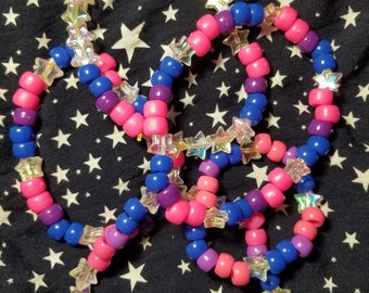 May include: Three colorful beaded bracelets with iridescent star-shaped beads. The bracelets are pink, blue, and purple.