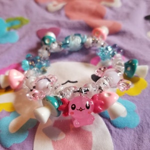 May include: A colorful charm bracelet with a pink axolotl charm, white and blue mushroom charms, and clear beads.
