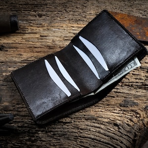 May include: A brown leather wallet with a billfold and card slots, open to reveal a &pound;10 note. The wallet is lying on a rustic wooden surface.
