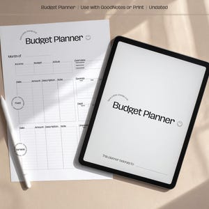 Könnte beinhalten: Ein weißer Budgetplaner mit dem Text "Budget Planner" liegt neben einem weißen Stift und einem Tablet. Der Planer hat Abschnitte für Einkommen, Budget und Notizen. Das Tablet zeigt ebenfalls "Budget Planner".
