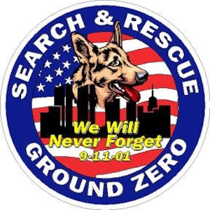 May include: A round, blue and red sticker with the words "Search & Rescue Ground Zero" in a white circle around the edge. Inside the circle is a German Shepherd dog's head with a red tongue sticking out, a cityscape, and the words "We Will Never Forget 9-11-01". The background is a red, white, and blue American flag.