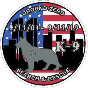 Könnte beinhalten: Ein runder Patch in den Farben der amerikanischen Flagge, rot, weiß und blau, mit einer schwarzen Silhouette einer Stadtkulisse und einem grauen Schäferhund, der davor steht. Der Text "GROUND ZERO 9/11/01-9/11/19 K-9 SEARCH & RESCUE" ist auf dem Patch aufgedruckt.