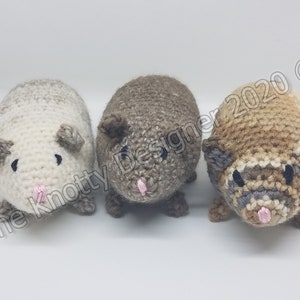 Peut inclure: Trois peluches de cobaye en crochet. Les peluches sont faites avec des fils de diff&eacute;rentes couleurs, dont le blanc, le brun et le beige. Chaque peluche a des yeux noirs et un nez rose.