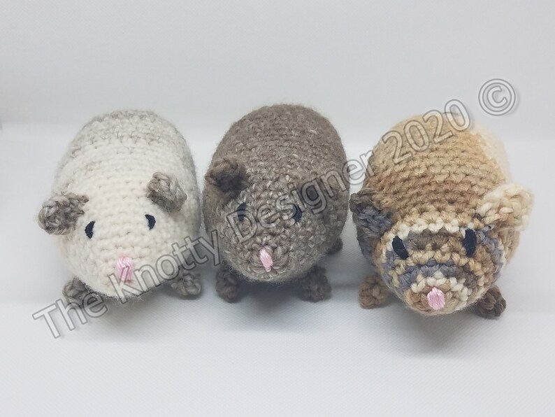 Peut inclure: Trois peluches de cobaye en crochet. Les peluches sont faites avec des fils de diff&eacute;rentes couleurs, dont le blanc, le brun et le beige. Chaque peluche a des yeux noirs et un nez rose.